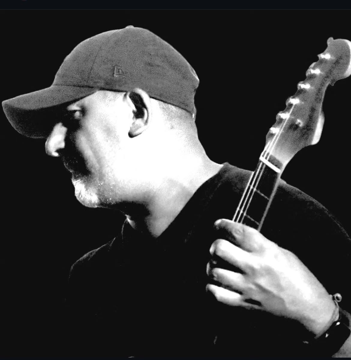 Black-and-white portrait of Jonathan in a cap, playing guitar